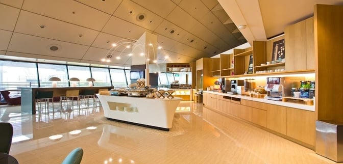 The Ambassador Transit Lounge at Singapore Changi Airport features a self-serve food area with various snacks and beverages available.