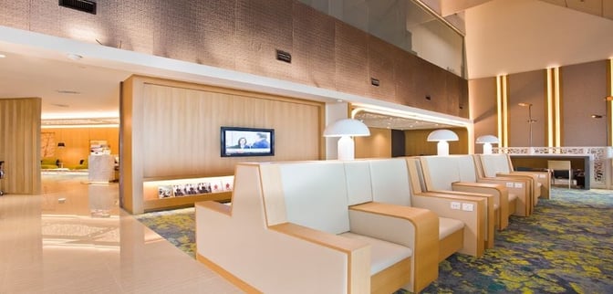 The seating area in the Ambassador Transit Lounge at Singapore Changi Airport features individual chairs with built-in power outlets and nearby lighting.