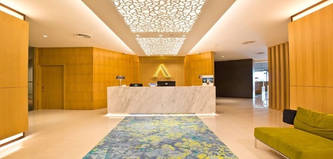 The reception area of the Ambassador Transit Lounge at Singapore Changi Airport features a check-in desk and seating for arriving guests.