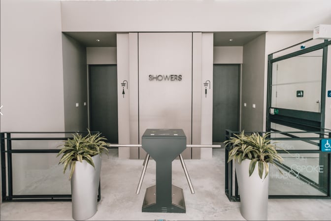 The shower entrance at Hub & Spoke, Changi Airport, features a turnstile and signage, providing access to shower facilities.