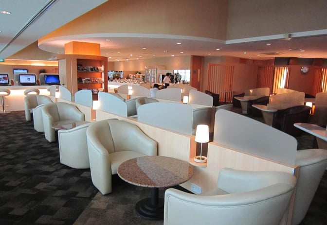 The SATS Premier Lounge at Singapore Changi Airport features individual seating with small tables and a self-serve food area.