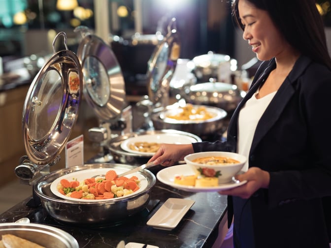 A guest serves herself from a buffet with various hot dishes at the SATS Premier Lounge Terminal 3 in Singapore Changi Airport.