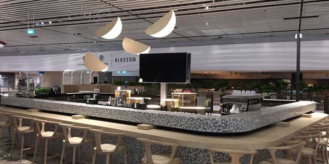 The bar area at Blossom Lounge in Singapore Changi Airport features counter seating and a variety of beverage options.
