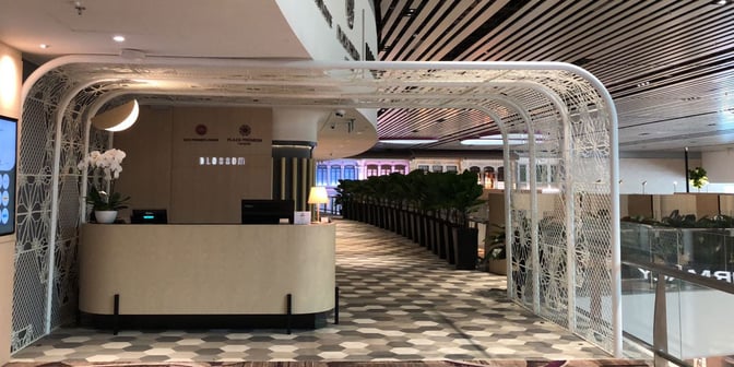 The entrance to the BLOSSOM Lounge at Singapore Changi Airport features a reception desk and decorative partitioning.