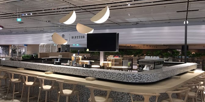 The bar area at Blossom Lounge in Singapore Changi Airport features counter seating and a variety of beverage options.