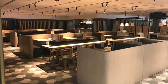 Booth seating at the BLOSSOM Lounge in Singapore Changi Airport provides semi-private dining areas with tables and chairs for travelers.