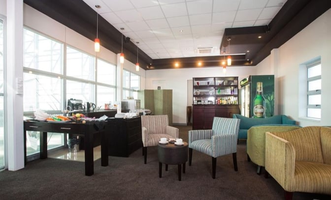 The Pula Lounge at Sir Seretse Khama International Airport features a seating area with armchairs and a self-serve snack station.