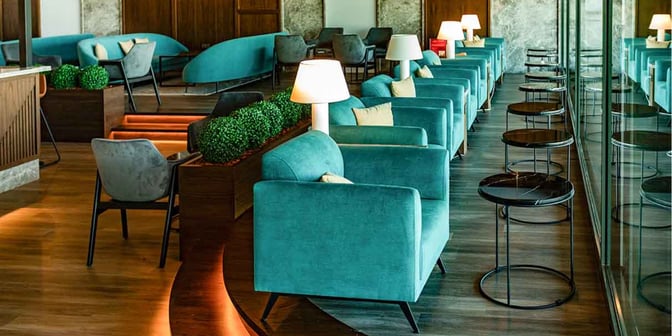 The seating area in Primeclass Lounge at Skopje International Airport features armchairs and side tables arranged along a glass wall.
