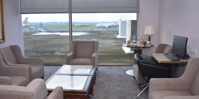 The Saphire Lounge at Soekarno-Hatta International Airport features comfortable seating with a view of the runway and a computer station.