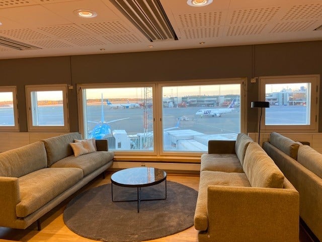 The seating area in the Pearl Lounge at Stockholm Arlanda Airport offers comfortable couches with views of the airport runway.