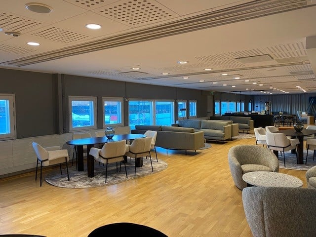 The seating area in Pearl Lounge at Stockholm Arlanda Airport features tables and chairs with views of the tarmac.