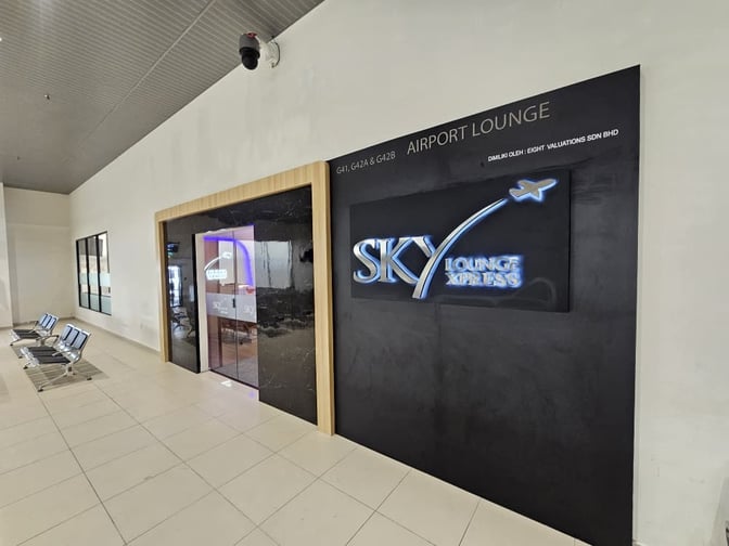The entrance to Sky Lounge Xpress at Sultan Abdul Aziz Shah Airport features a prominent sign and adjacent seating area.