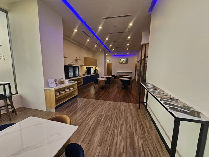 The Sky Lounge Xpress at Sultan Abdul Aziz Shah Airport features a self-serve snack area and seating with tables for dining.