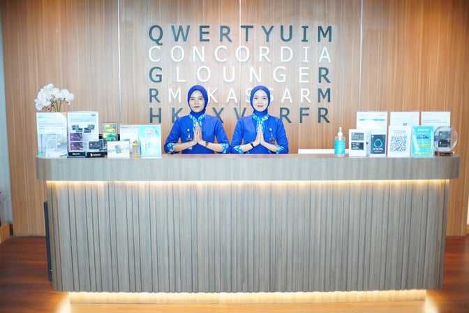 The reception desk at Concordia Lounge, Sultan Hasanuddin International Airport, features staff ready to assist guests with lounge services.