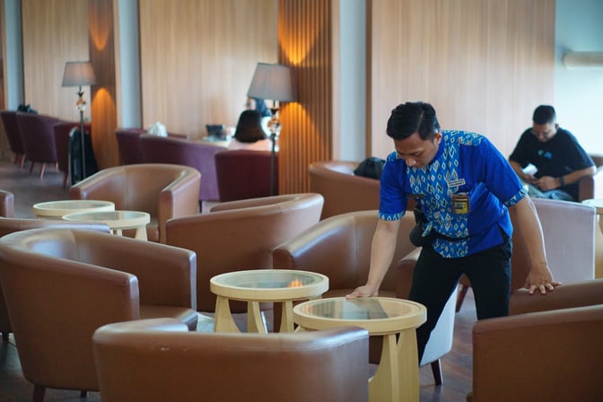 The seating area in Concordia Lounge at Sultan Hasanuddin International Airport features comfortable chairs and tables, with staff attending to the space.