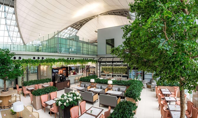 The Coral Executive Lounge at Suvarnabhumi Airport features a seating area with tables, chairs, and a self-serve beverage station.