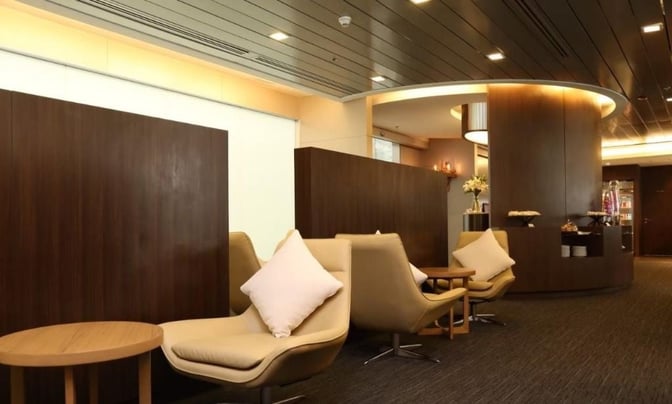 The Miracle First and Business Class Lounge at Suvarnabhumi Airport features comfortable seating with side tables and a visible refreshment area.