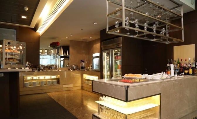 The Miracle First and Business Class Lounge at Suvarnabhumi Airport features a self-serve buffet with hot dishes and a bar area.