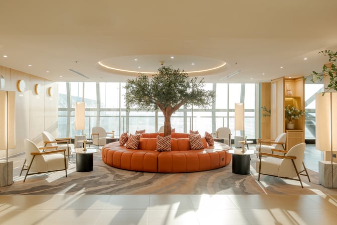 The Coral Finest Business Class Lounge Cocoon at Suvarnabhumi Airport features a central circular seating area with surrounding armchairs and tables.