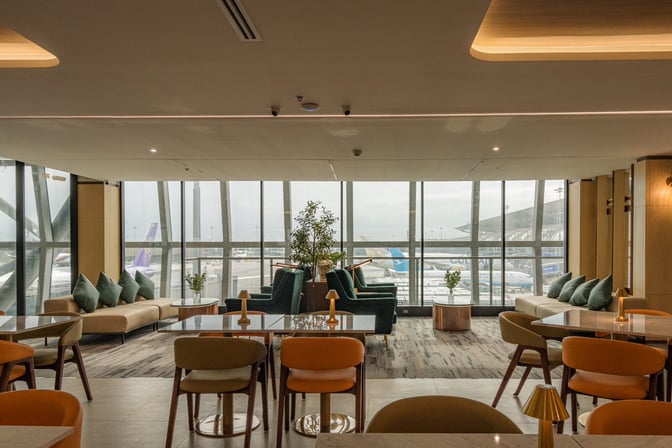 The Coral Finest Business Class Lounge at Suvarnabhumi Airport features seating with tables and views of the airport tarmac.