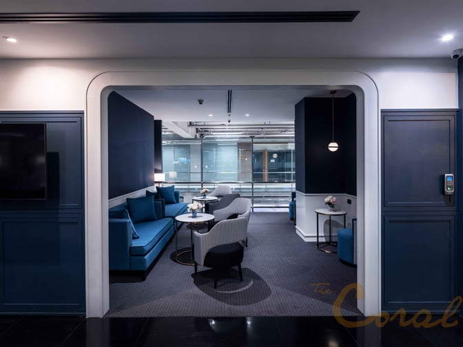 The Coral Finest Business Class Lounge at Suvarnabhumi Airport features a seating area with sofas and chairs near large windows.