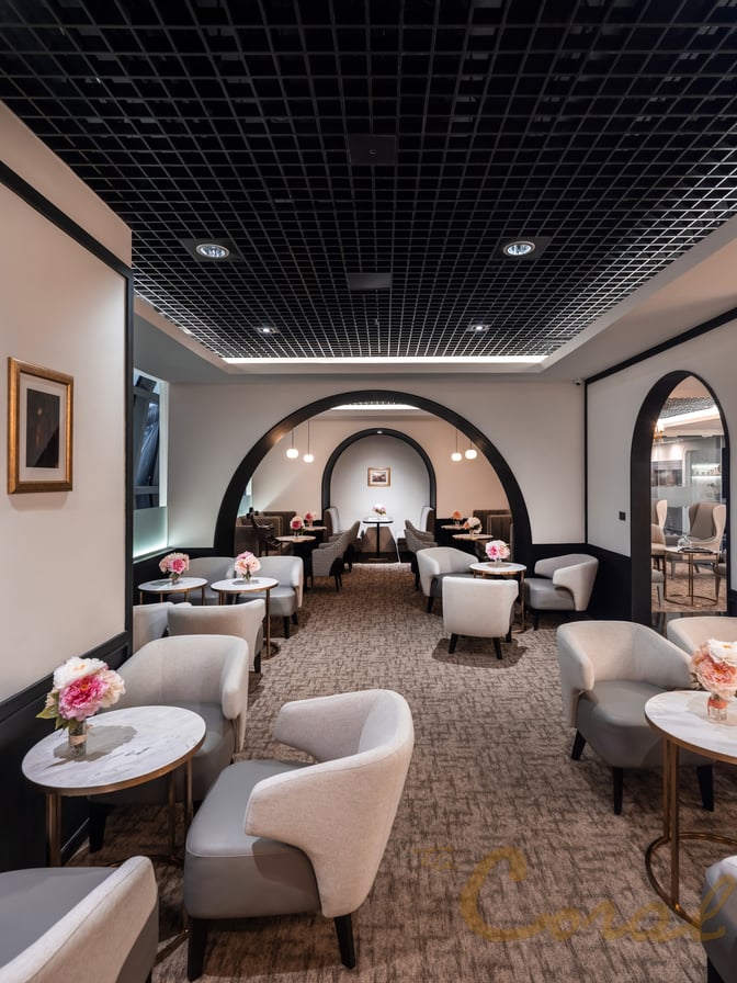 Seating area in The Coral First Class Lounge at Suvarnabhumi Airport features tables with armchairs arranged for passenger comfort and relaxation.