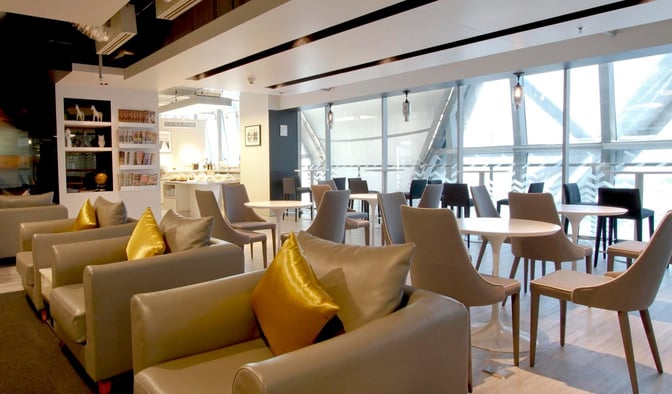 The Miracle Business Class Lounge at Suvarnabhumi Airport features comfortable seating and a self-serve food area with ample natural light.