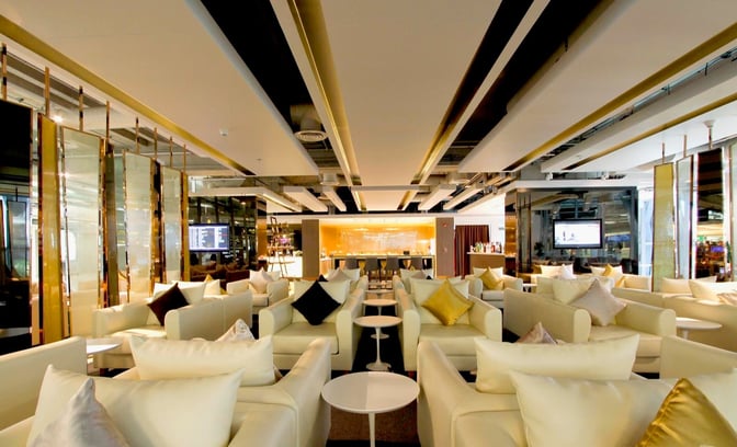 The Miracle Business Class Lounge at Suvarnabhumi Airport features a spacious seating area with armchairs and small tables for travelers.
