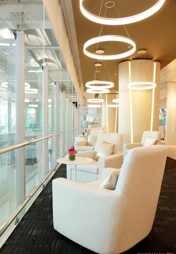 Comfortable seating in the Miracle First Class Lounge at Suvarnabhumi Airport offers views of the terminal through large windows.