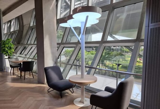 The seating area in Miracle Lounge at Suvarnabhumi Airport offers chairs and tables with views of the airport's exterior gardens.