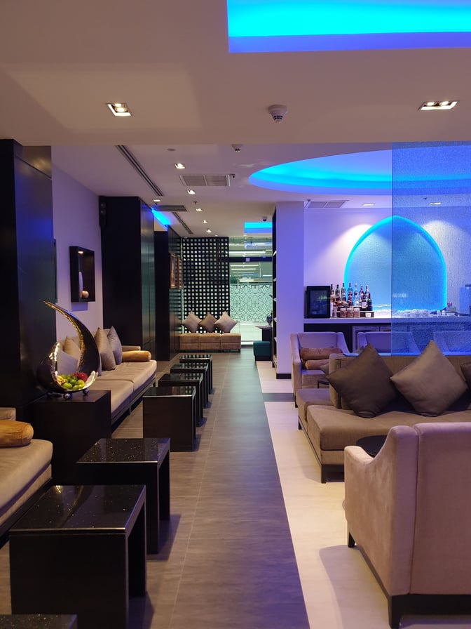 The Oman Air First and Business Class Lounge at Suvarnabhumi Airport features comfortable seating and a self-serve bar area.