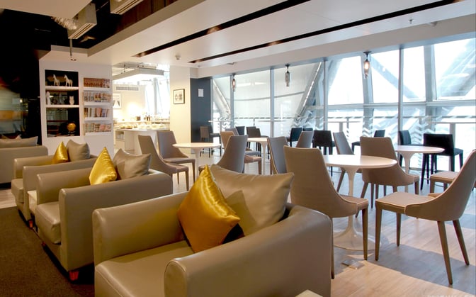 The Miracle Business Class Lounge at Suvarnabhumi Airport Concourse F features comfortable seating with armchairs and dining tables, offering a relaxing space for travelers.