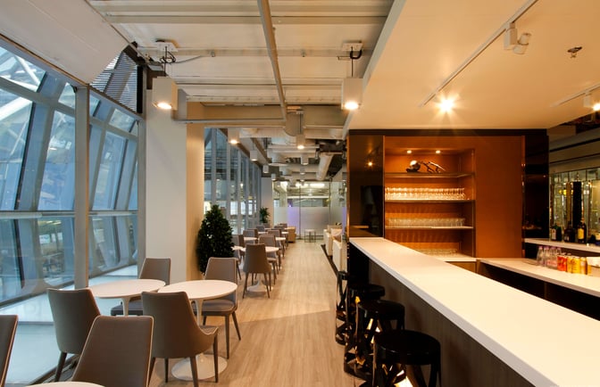 The Miracle Business Class Lounge at Suvarnabhumi Airport Concourse F features a bar with seating and adjacent tables for dining and relaxation.