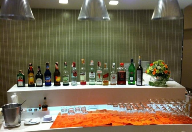 The Miracle First Class Lounge bar at Suvarnabhumi Airport offers a selection of spirits with glasses ready for service.