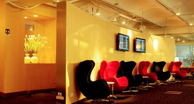 Seating area in the Miracle First Class Lounge at Suvarnabhumi Airport features modern chairs and flight information screens for passenger convenience.