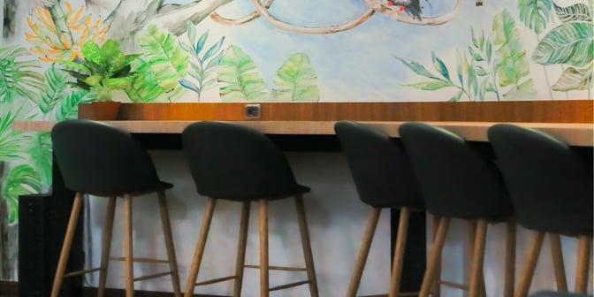 High stools at a counter in Concordia Lounge provide seating with a decorative wall featuring a nature-themed mural.