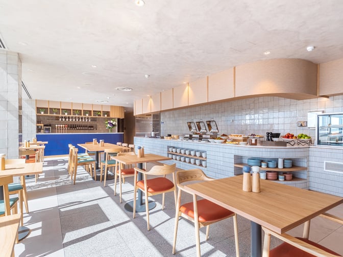 The dining area in the SkyTeam Lounge at Sydney Airport features self-serve food stations and ample table seating for guests.