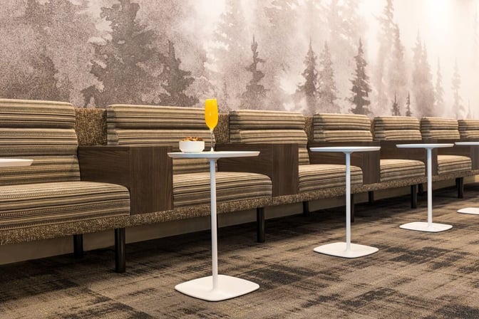 The seating area in the Escape Lounge at Syracuse Hancock International Airport features cushioned benches with individual tables for refreshments.