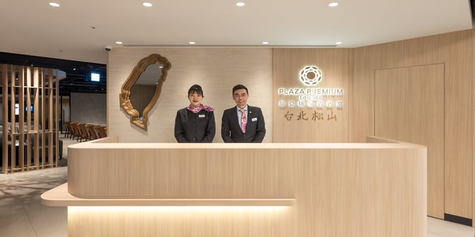 The reception area of Plaza Premium Lounge at Taipei Songshan Airport features a welcoming desk with staff ready to assist travelers.