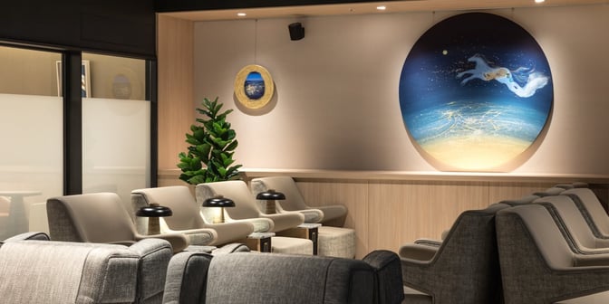 The seating area in the Plaza Premium Lounge at Taipei Songshan Airport features comfortable chairs and small tables with lamps.