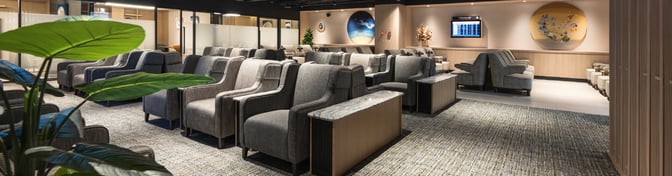 The seating area in Plaza Premium Lounge at Taipei Songshan Airport features rows of comfortable chairs with armrests and small side tables.