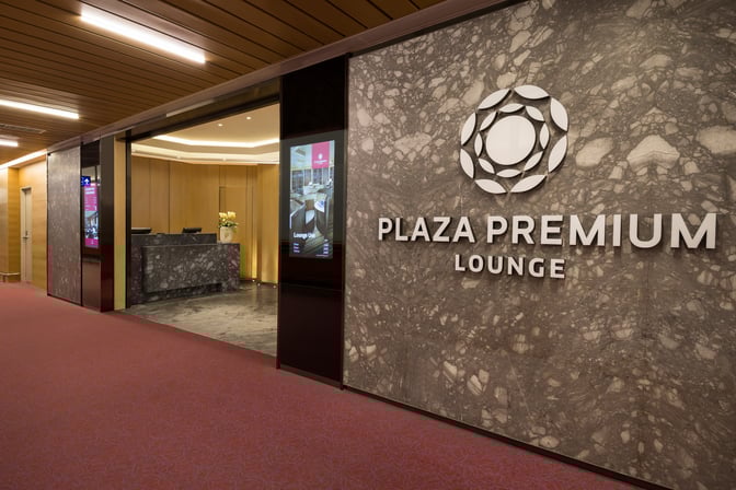 The entrance to Plaza Premium Lounge at Taiwan Taoyuan International Airport features a reception desk and digital information displays.