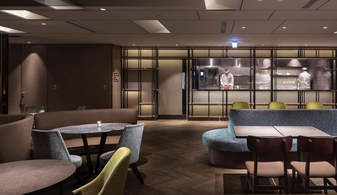 The Plaza Premium Lounge at Taiwan Taoyuan International Airport features a seating area with tables and a visible kitchen where chefs prepare food.