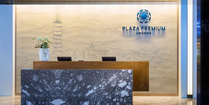 The reception desk at Plaza Premium Lounge, Zone A1, Taiwan Taoyuan International Airport, features a decorative wall and check-in counters.
