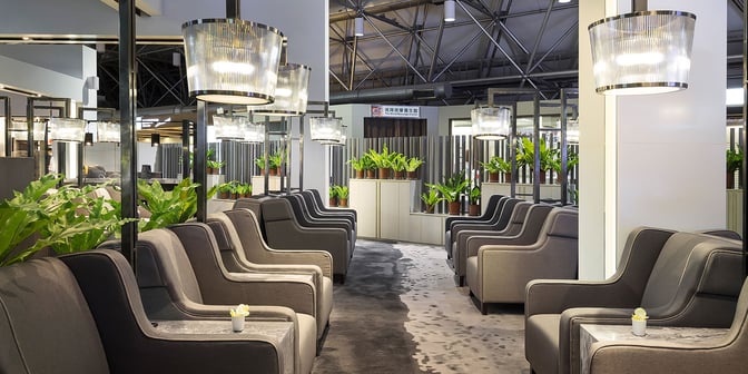 Comfortable seating in the Plaza Premium Lounge at Taiwan Taoyuan International Airport features armchairs and small tables, surrounded by potted plants.