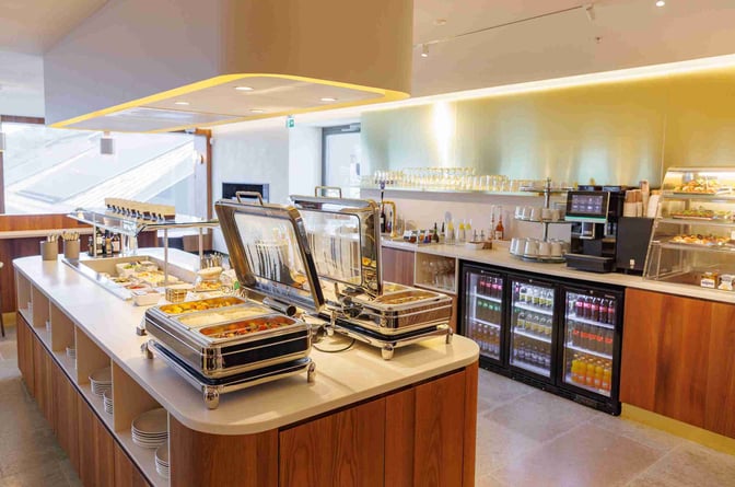 The Tallinn Airport LHV Lounge features a self-serve food area with hot dishes, beverages, and a coffee machine available for guests.