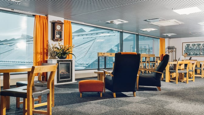 The Tallinn Airport LHV Lounge features comfortable seating with tables, a fireplace, and large windows offering views of the airport.