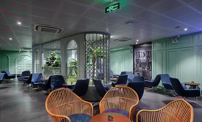 The seating area in Le Saigonnais Business Lounge at Tan Son Nhat Airport features comfortable chairs and tables with a central plant display.