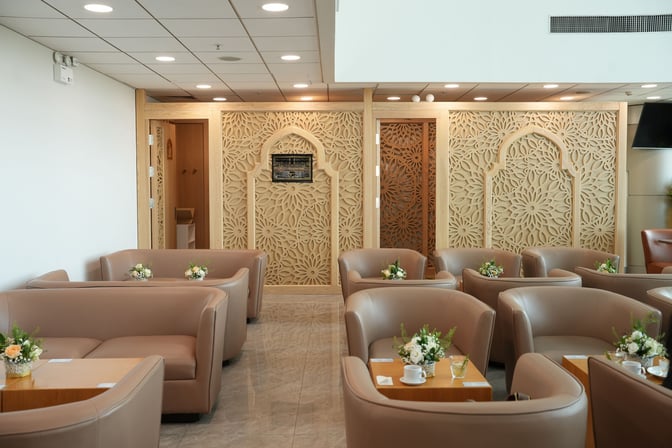 The seating area at Jasmine Halal Lounge features comfortable chairs and tables with decorative partitions, providing a relaxing space for travelers.