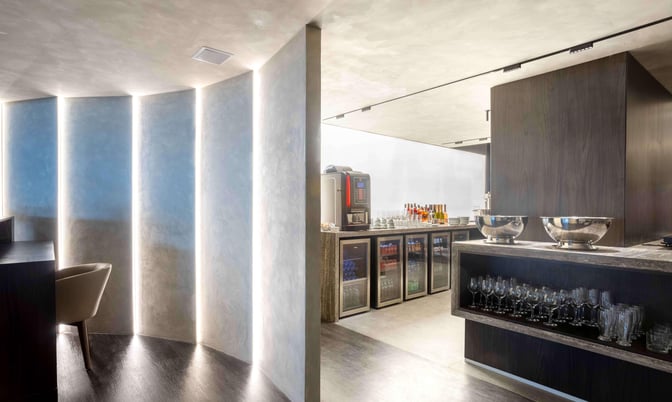 The BRT Lounge at Tancredo Neves International Airport features a self-serve beverage area with refrigerators, glassware, and a coffee machine.